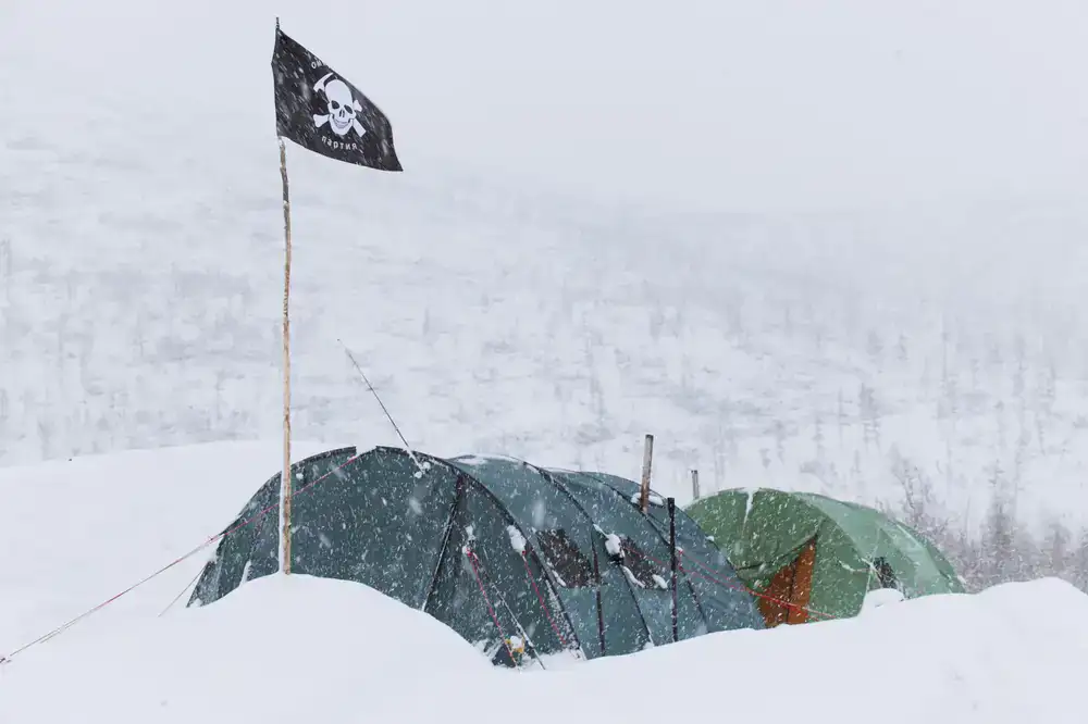 Players building a camp in a deep snow blizzard